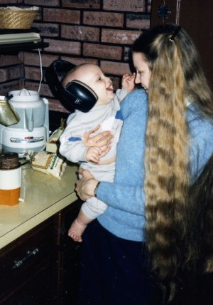 Will (7 mos.) wearing noise protectors and "helping" make organic baby cereal in 1985.